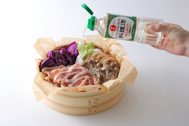 日の出みりんレシピ 豚肉と彩り野菜のせいろ蒸しに日の出料理酒をかけているところ